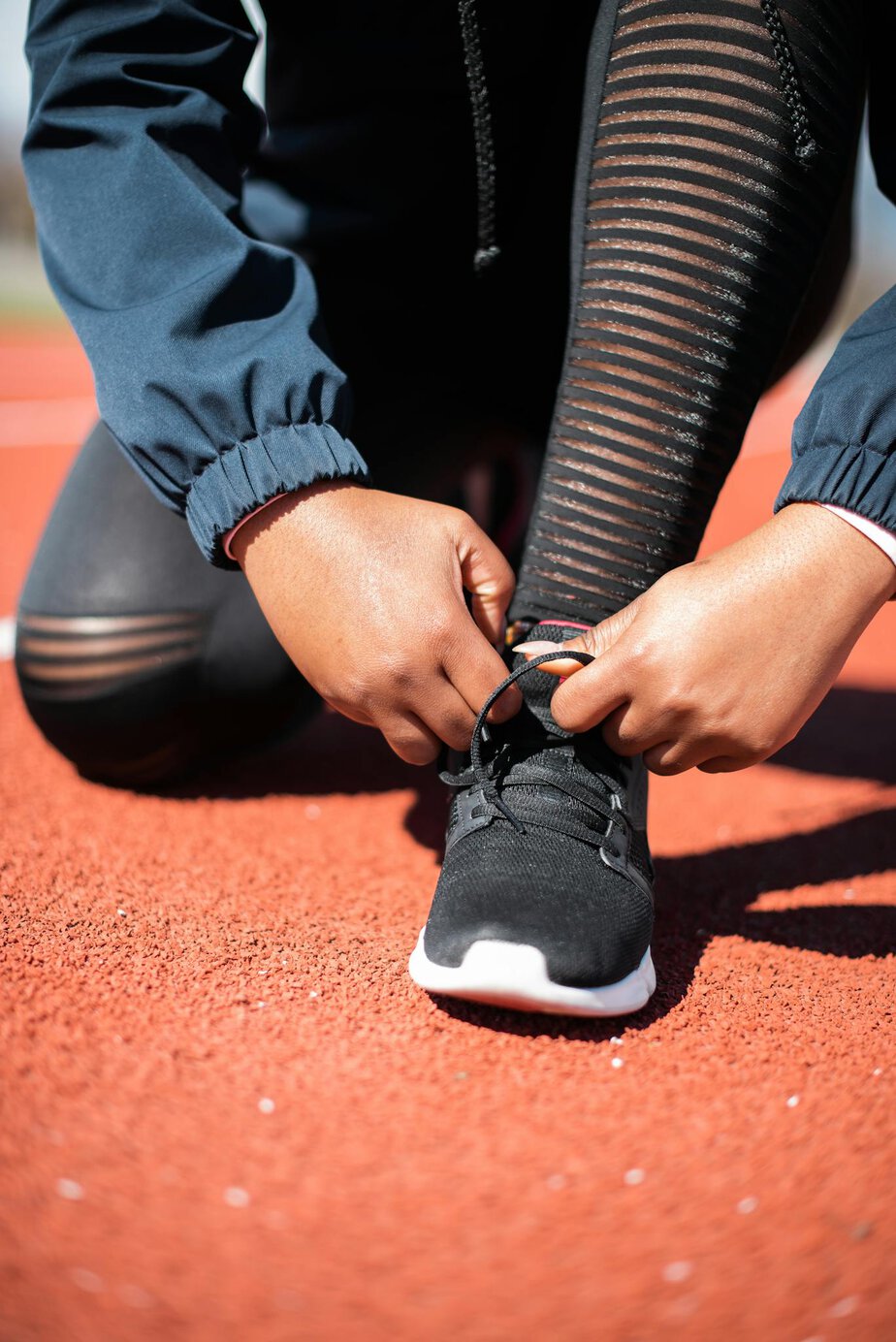 hands tying shoelaces on running track preparing